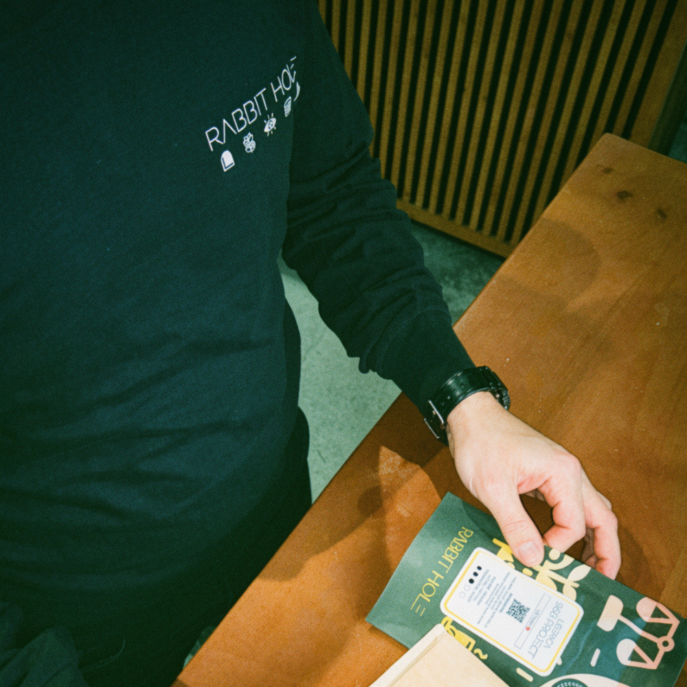 David Lalonde featured wearing a black long sleeve tshirt with 'Rabbit Hole' text, holding a bag of coffee beans on a wooden table.